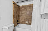 This bathroom features a classic white bathtub with a dark bronze faucet and showerhead, complemented by warm-toned tiled walls.
