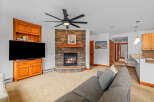Cozy living room featuring a stone fireplace with a wooden mantel and a large flat-screen TV.