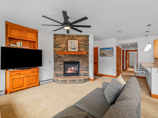 Cozy living room featuring a stone fireplace with a wooden mantel and a large flat-screen TV.