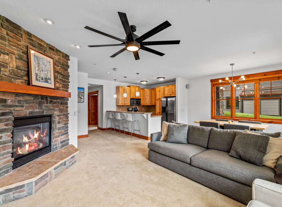 Cozy living room featuring a stone fireplace with a wooden mantel and a large gray sectional sofa.