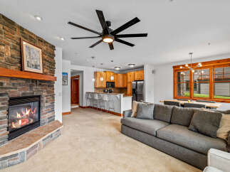Cozy living room featuring a stone fireplace with a wooden mantel and a large gray sectional sofa.