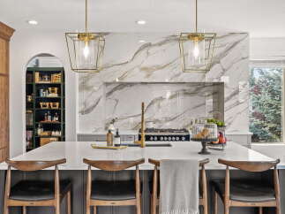 Experience luxury in this stunning kitchen, featuring a dramatic marble backsplash and elegant gold pendant lights.