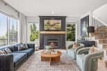 Experience luxury living in this stunning living room, featuring a grand fireplace as the centerpiece and expansive windows offering breathtaking views.
