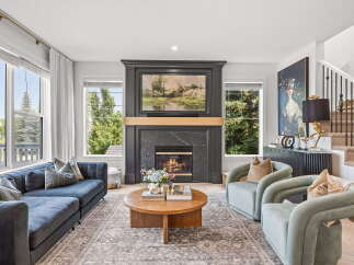 Experience luxury living in this stunning living room, featuring a grand fireplace as the centerpiece and expansive windows offering breathtaking views.