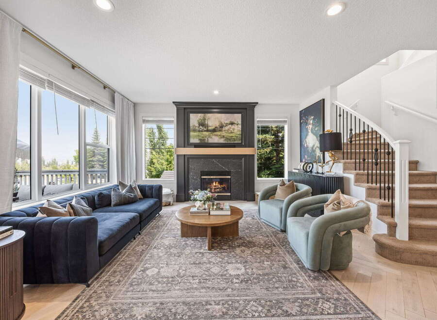 Experience luxurious living in this stunning living room, featuring a grand fireplace as the centerpiece and expansive windows offering picturesque views.