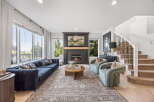 Experience luxurious living in this stunning living room, featuring a grand fireplace as the centerpiece and expansive windows offering picturesque views.
