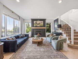 Experience luxurious living in this stunning living room, featuring a grand fireplace as the centerpiece and expansive windows offering picturesque views.