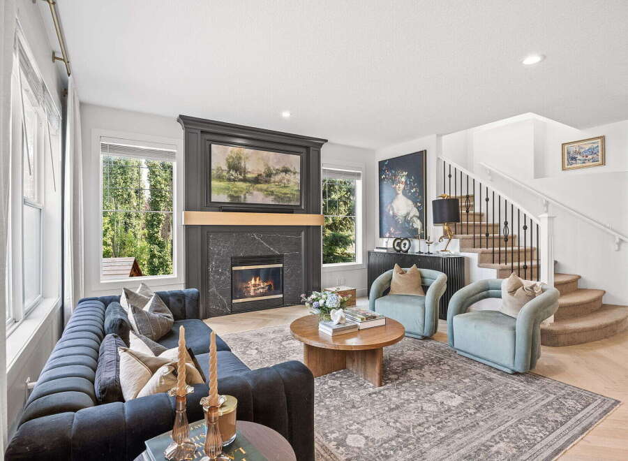 Experience luxurious living in this stunning living room, featuring a grand fireplace with a marble surround and a captivating landscape painting above.