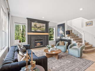 Experience luxurious living in this stunning living room, featuring a grand fireplace with a marble surround and a captivating landscape painting above.