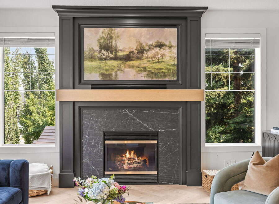 Experience cozy evenings by this stunning fireplace, featuring a dark marble surround and a beautiful landscape painting above.