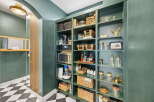 Discover the ultimate pantry organization with this beautifully designed space, featuring deep green shelving stocked with a variety of baskets, jars, and appliances.