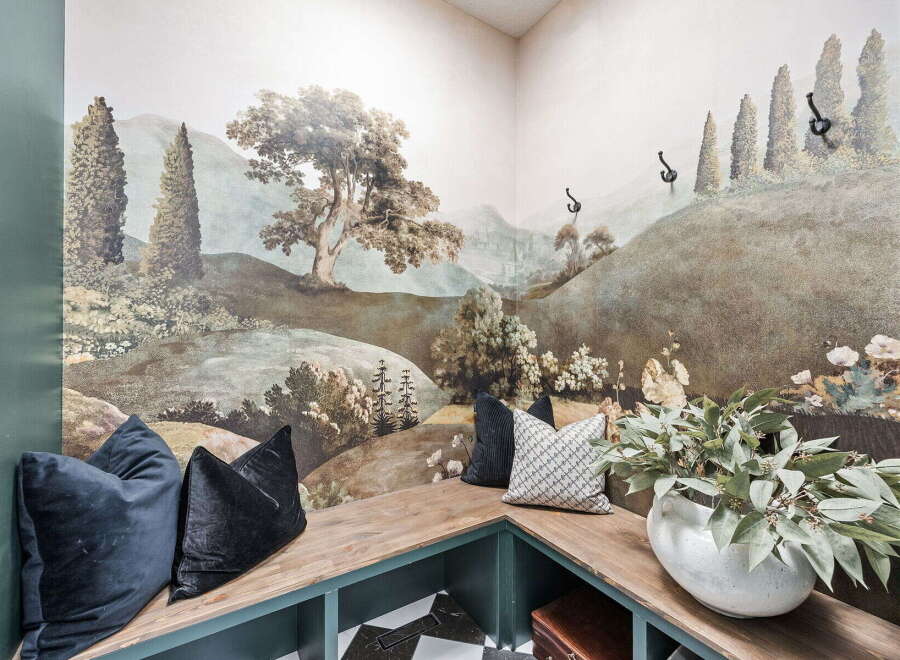 Step into a whimsical retreat with this charming corner banquette, featuring a stunning mural that transports you to a serene landscape.