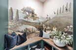 Step into a whimsical retreat with this charming corner banquette, featuring a stunning mural that transports you to a serene landscape.