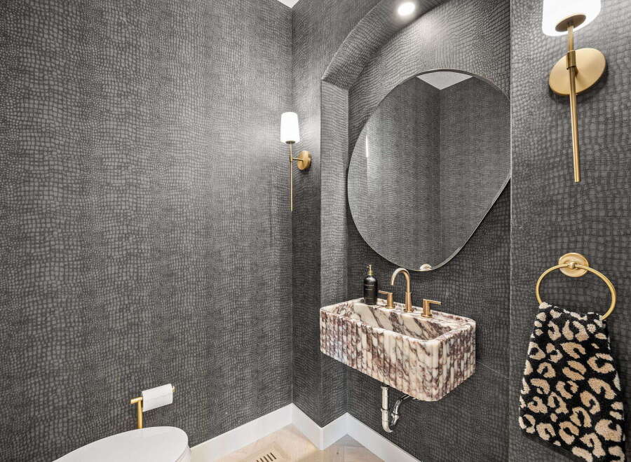 This powder room features a striking dark textured wallpaper that adds depth and sophistication.