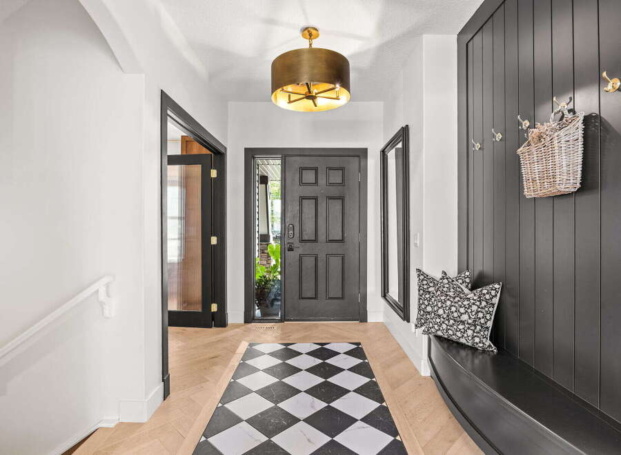 Step into this inviting entryway featuring a striking black paneled wall with decorative hooks and a woven basket.