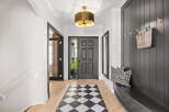 Step into this inviting entryway featuring a striking black paneled wall with decorative hooks and a woven basket.