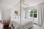Experience whimsical charm in this enchanting bedroom, featuring a beautiful white canopy bed adorned with delicate floral bedding.