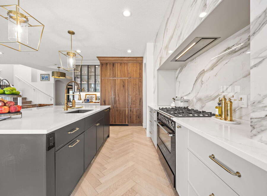 Experience luxury in this stunning modern kitchen, featuring a large island with a waterfall countertop and sleek dark cabinetry.