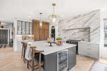 Experience luxury in this stunning kitchen, featuring a dramatic marble backsplash and a spacious island with a built-in wine fridge.