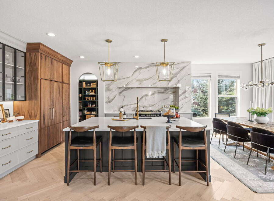 Experience luxury in this stunning modern kitchen, featuring a grand island with marble backsplash and elegant pendant lighting.