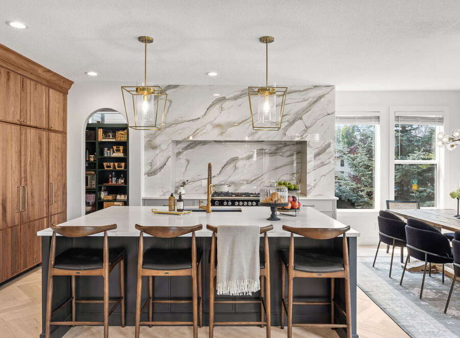 Experience luxury in this stunning kitchen featuring a dramatic marble backsplash and a spacious island with seating.