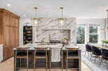 Experience luxury in this stunning kitchen featuring a dramatic marble backsplash and a spacious island with seating.