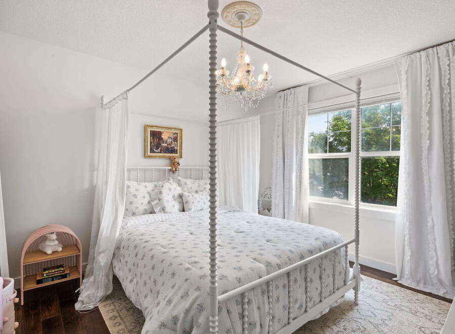 Experience whimsical charm in this enchanting bedroom, featuring a beautiful white canopy bed adorned with delicate floral bedding.