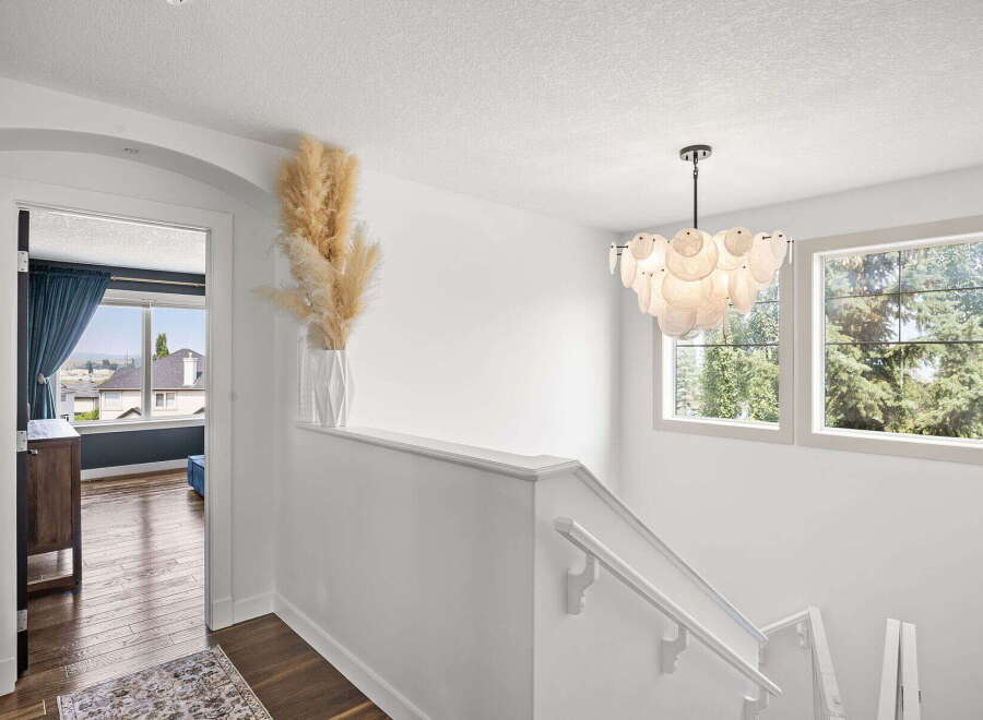 Ascend to the upper level of this stunning home via a beautifully lit staircase, adorned with a modern chandelier.