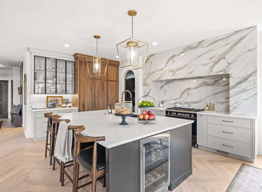 Experience luxury in this stunning kitchen, featuring a dramatic marble backsplash and a spacious island with a built-in wine fridge.