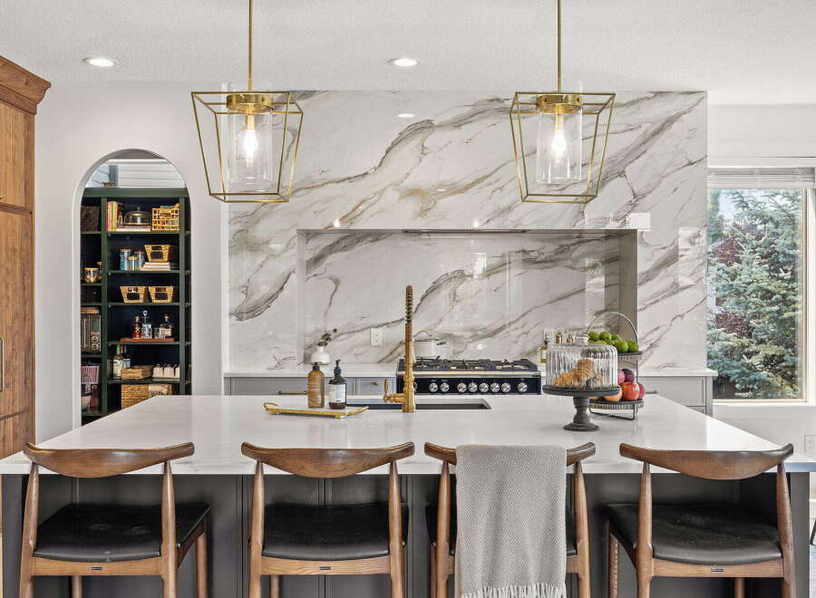 Experience luxury in this stunning kitchen, featuring a dramatic marble backsplash and elegant gold pendant lights.