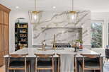 Experience luxury in this stunning kitchen, featuring a dramatic marble backsplash and elegant gold pendant lights.