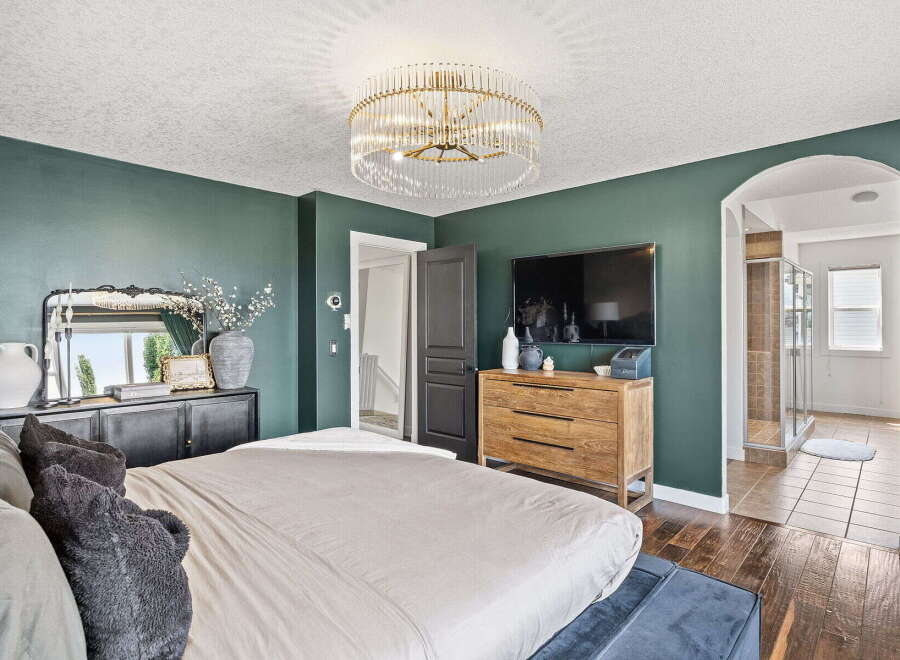 Experience luxury in this master suite featuring a stunning crystal chandelier and deep emerald walls.