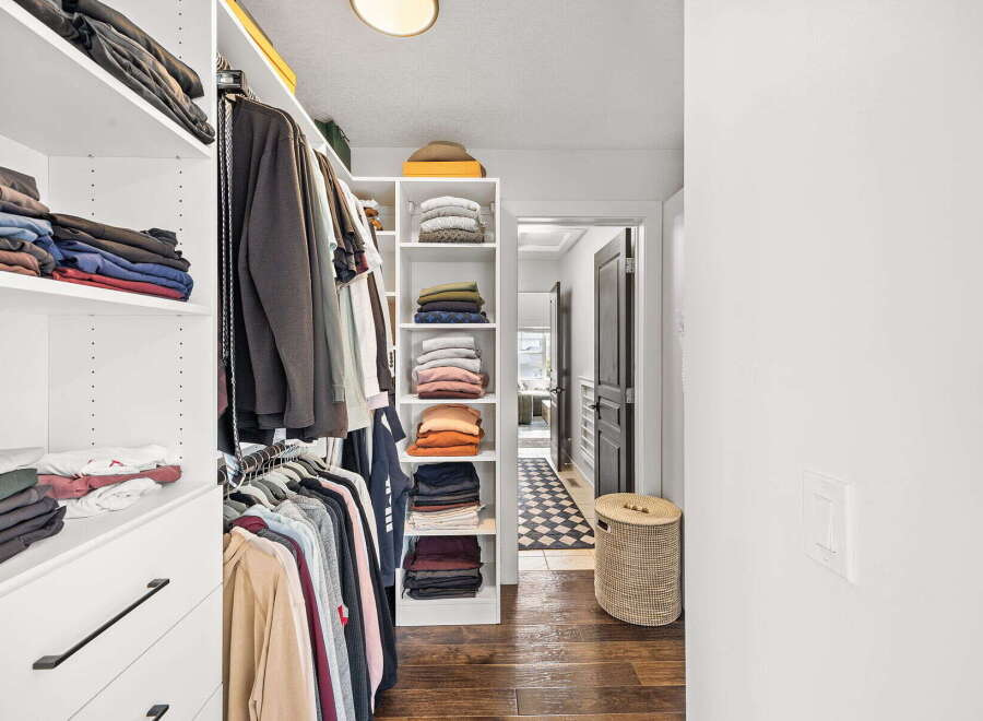 Discover organized living in this spacious walk-in closet, featuring ample shelving and hanging space for all your clothing needs.