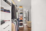 Discover organized living in this spacious walk-in closet, featuring ample shelving and hanging space for all your clothing needs.