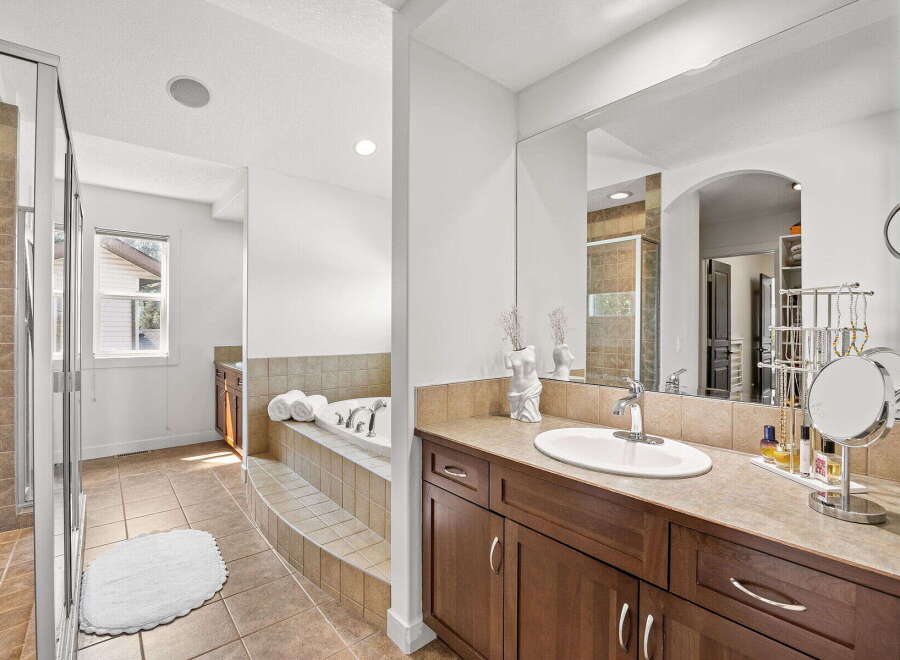 Indulge in luxury with this spacious bathroom featuring a large soaking tub and a separate glass-enclosed shower.