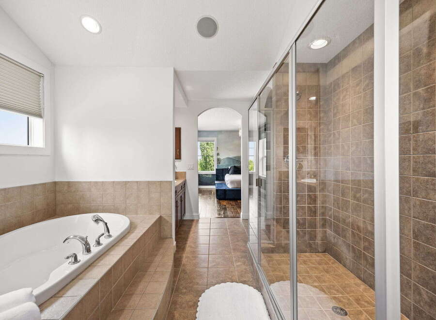 Indulge in luxury with this spacious master bathroom, featuring a deep soaking tub perfect for relaxation and a separate, beautifully tiled walk-in shower.