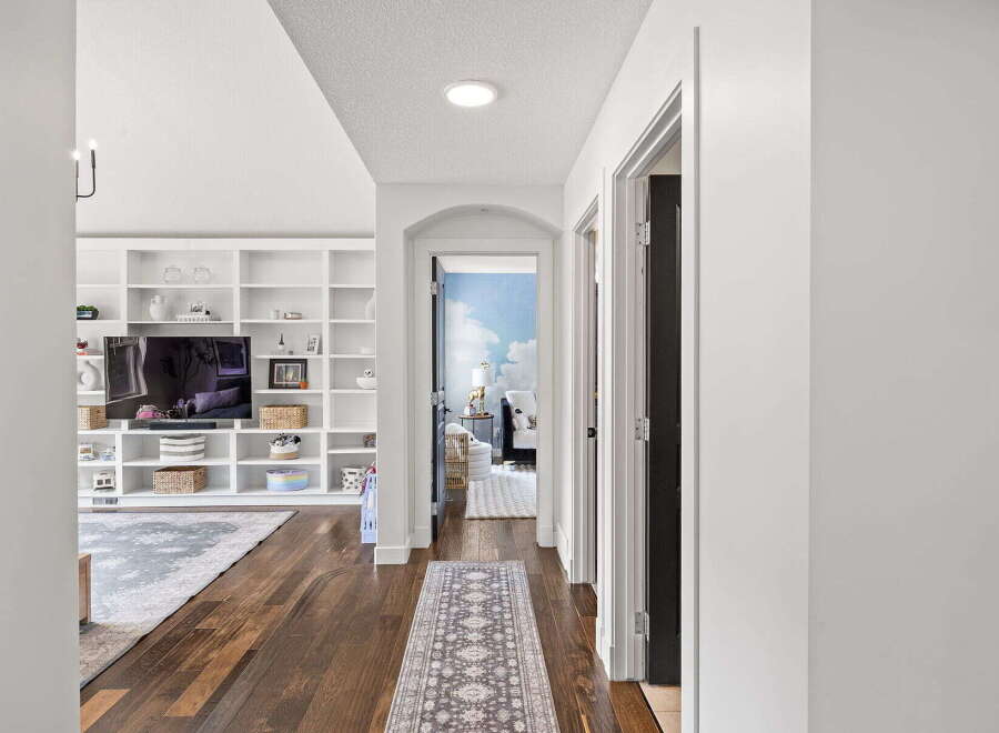 Step into this inviting hallway, featuring rich hardwood floors and a stylish runner leading to an arched doorway.