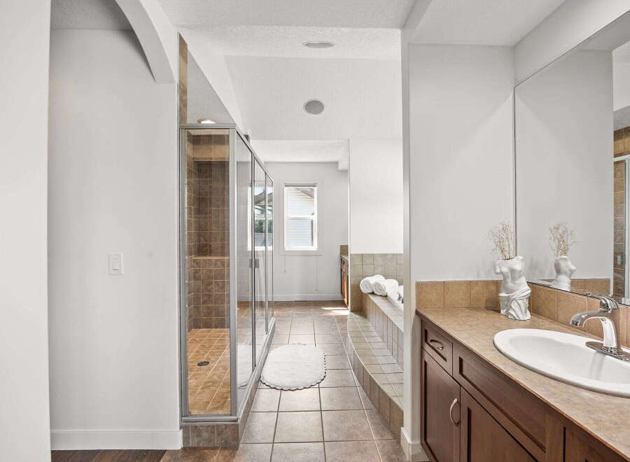 This spacious bathroom features a luxurious walk-in shower with tiled walls and a glass enclosure, perfect for a spa-like experience.