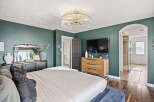 Experience luxury in this master suite featuring a stunning crystal chandelier and deep emerald walls.