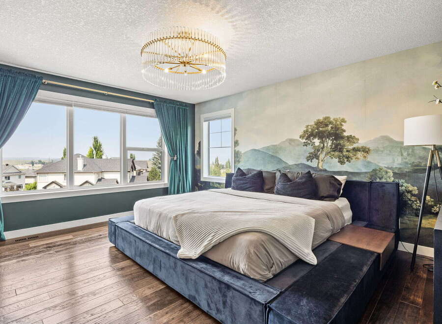 Experience luxury in this master bedroom, featuring a stunning landscape mural and plush velvet bed.
