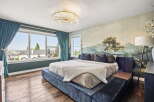Experience luxury in this master bedroom, featuring a stunning landscape mural and plush velvet bed.