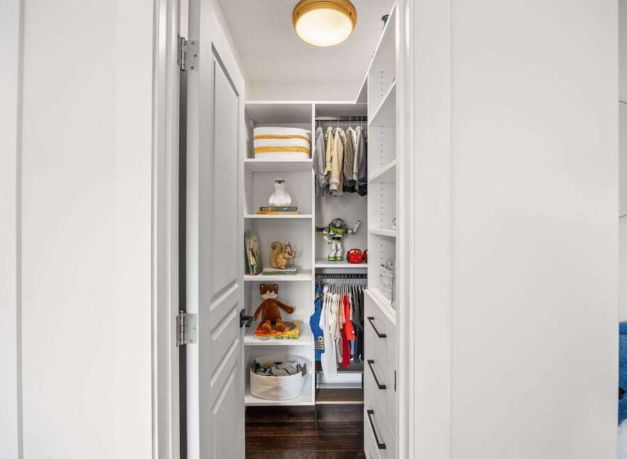 Discover organized living with this charming walk-in closet, featuring ample shelving and hanging space for all your essentials.