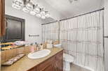 This bathroom features a modern vanity with a sleek countertop and a deep sink, complemented by a stylish crystal chandelier light fixture.