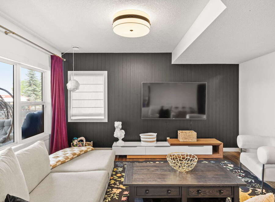 Step into this stylish living room featuring a modern entertainment center against a dark paneled accent wall, perfect for movie nights.