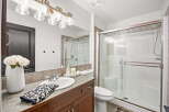 This bathroom features a spacious vanity with a large mirror and elegant lighting, complemented by a modern glass-enclosed shower.