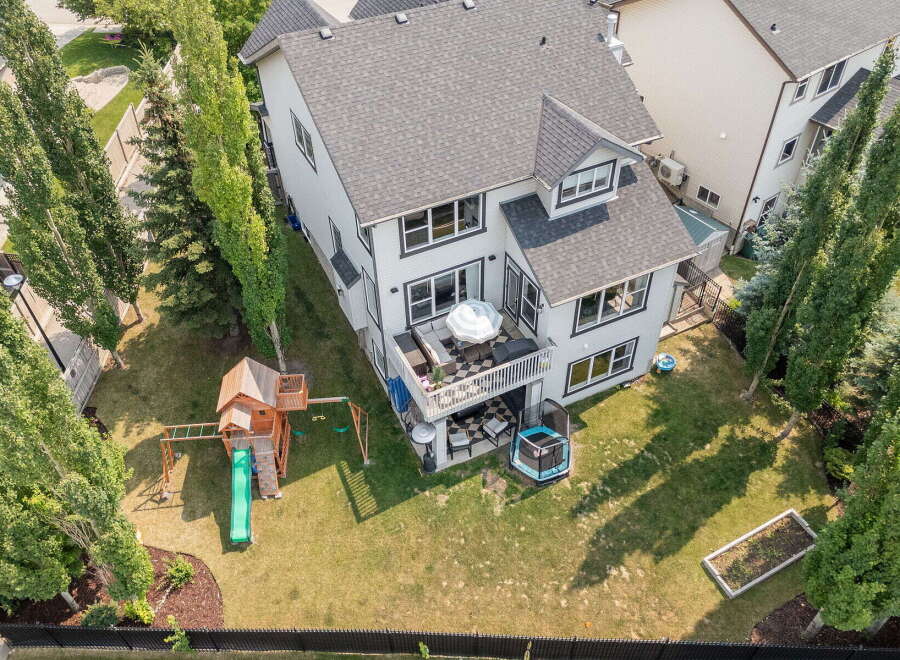 Enjoy outdoor living with this spacious backyard featuring a multi-level deck perfect for entertaining, a fun-filled playground, and a trampoline for endless family enjoyment.