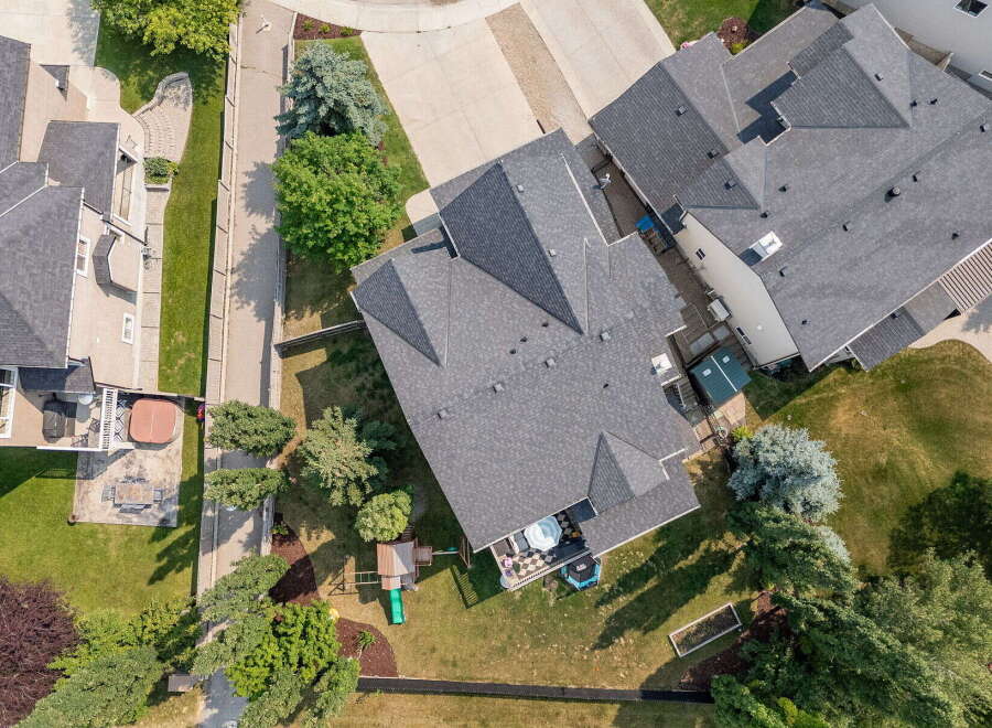 Discover this stunning aerial view showcasing a beautifully landscaped backyard with a private hot tub and a children's playset.