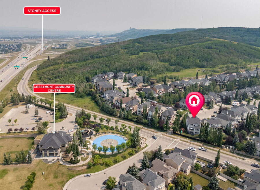 Discover this stunning aerial view of a suburban neighborhood featuring a mix of modern and traditional homes, nestled beside a lush green hillside and a winding highway.