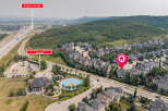 Discover this stunning aerial view of a suburban neighborhood featuring a mix of modern and traditional homes, nestled beside a lush green hillside and a winding highway.