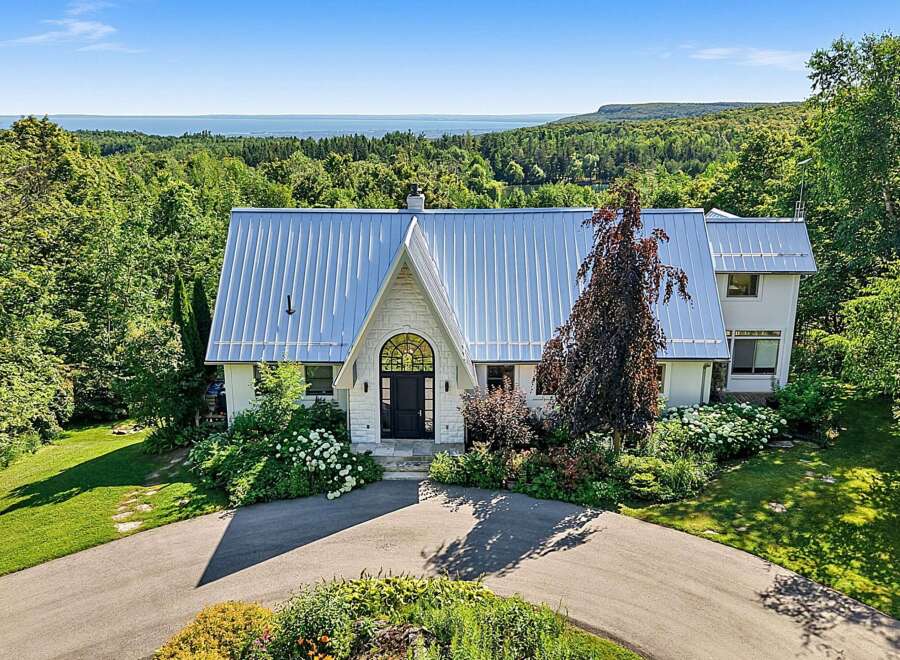 Nestled amidst lush greenery, this stunning property offers breathtaking panoramic views of the distant water and rolling hills.